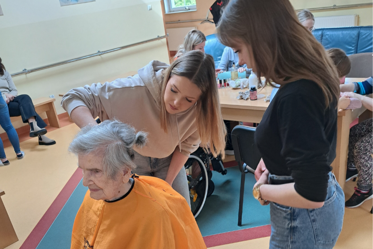 Uczestniczki Hufca Pracy w Elblągu układają fryzurę pensjonariuszce DPS Niezapominajka 