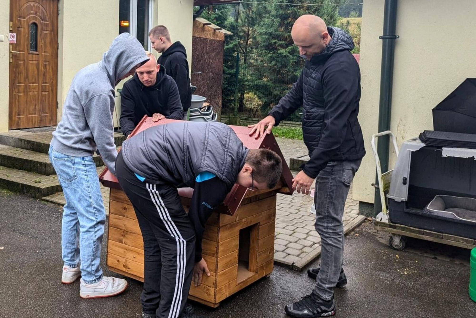 Młodzież z opiekunem ustawiają i oglądają budę